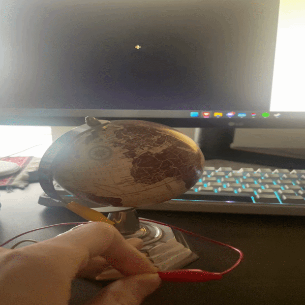 Testing a decorative globe as a conductive object out of curiosity, touching the metal base to see if it completes a circuit and triggers a response in the p5.js sketch.
